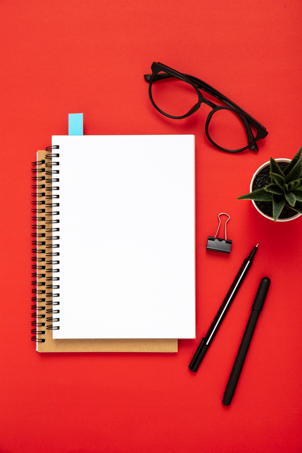 arrangement-desk-elements-with-empty-notebook-red-background